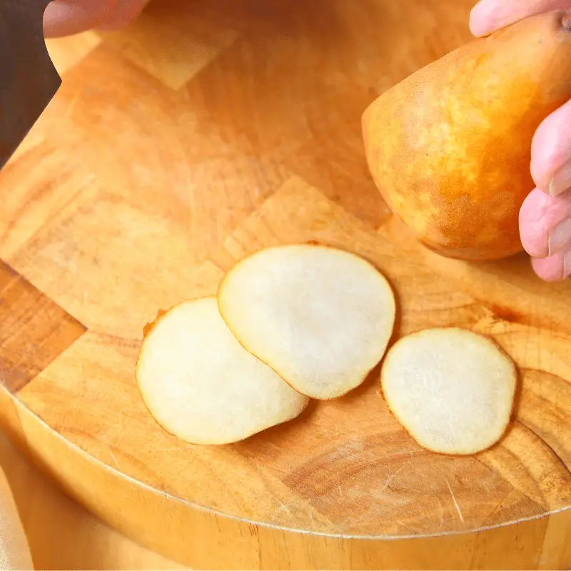 Three very thin slices of pear on a chopping board.