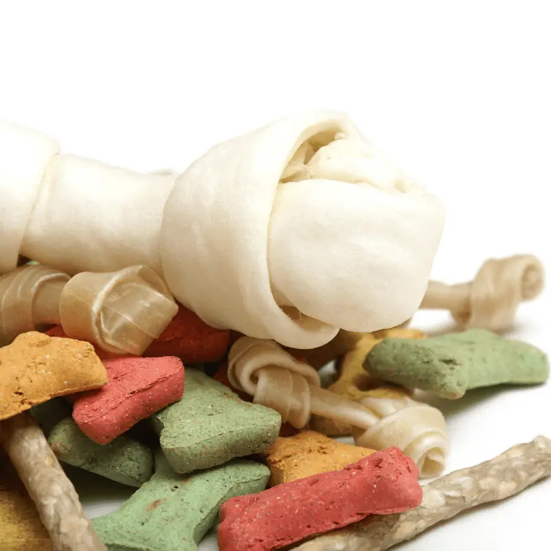 A pile of dog treats, bones, chews, and all different colours